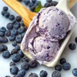 No-churn blueberry ice cream in a bowl, topped with fresh blueberries