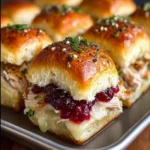 Baked cranberry turkey sliders topped with Havarti cheese and poppy seeds