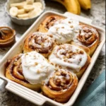 Banana bread cinnamon rolls drizzled with icing on a grey plate