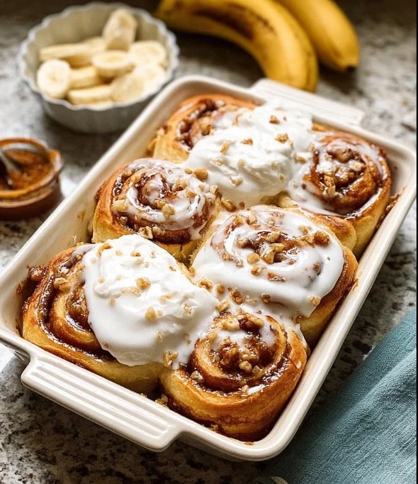 Banana bread cinnamon rolls drizzled with icing on a grey plate