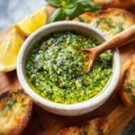 Homemade basil pesto in a dish garnished with pine nuts and fresh basil leaves.