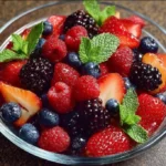 A colorful bowl of fresh berry fruit salad with strawberries, blueberries, and raspberries.