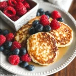 Fluffy cottage cheese pancakes served with fresh fruits and syrup on a plate