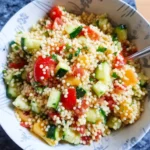 Colorful couscous salad with vegetables and herbs in a bowl
