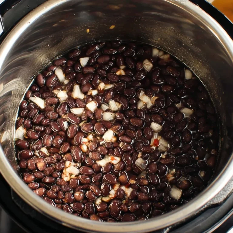Bowl of creamy Instant Pot black beans garnished with fresh herbs