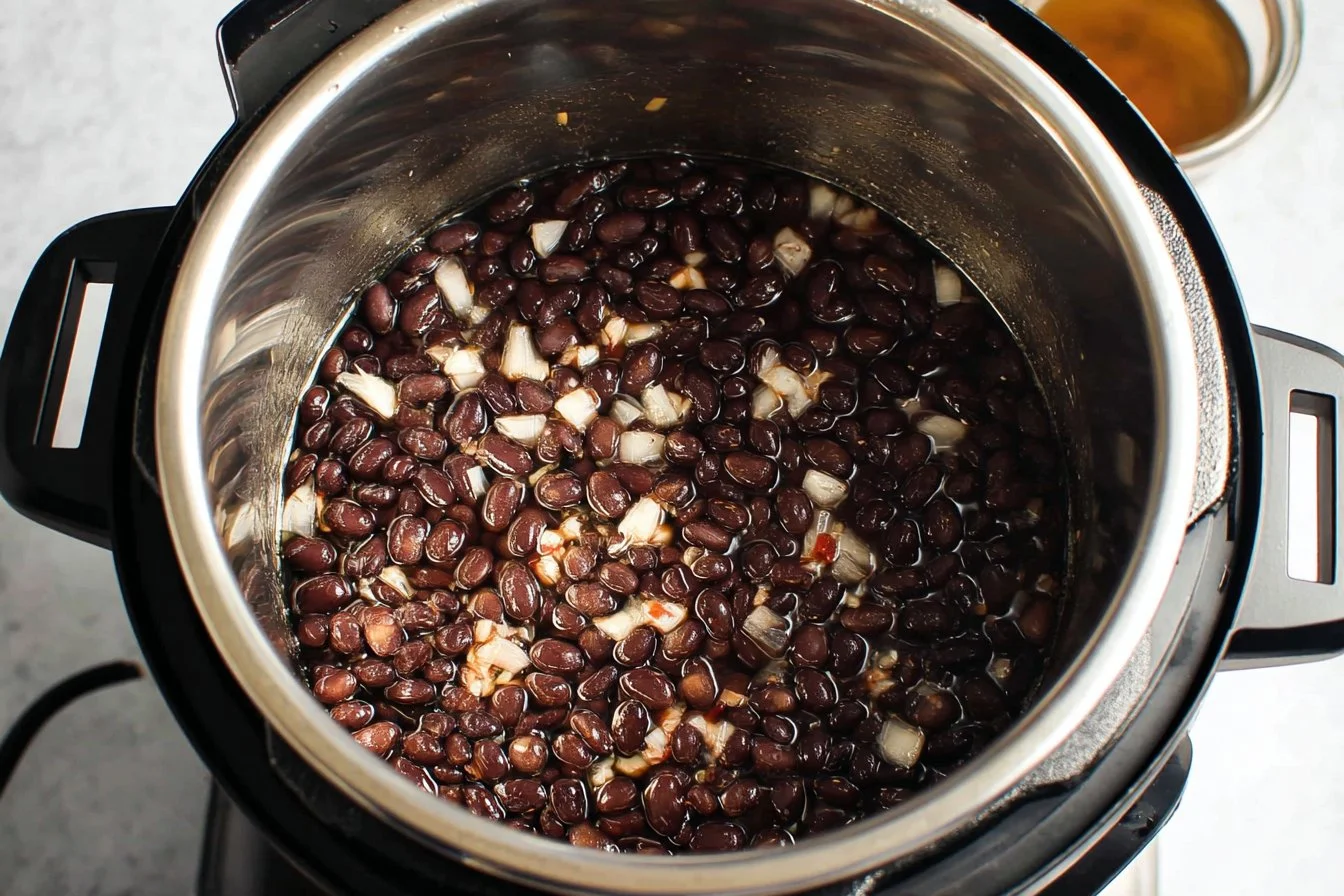 Bowl of creamy Instant Pot black beans garnished with fresh herbs