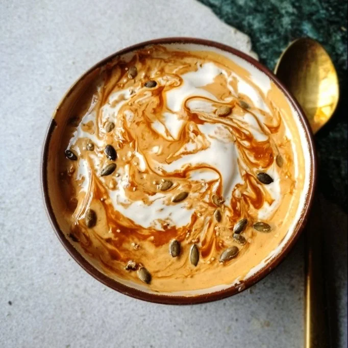 A bowl of pumpkin pie yogurt topped with whipped cream and cinnamon.