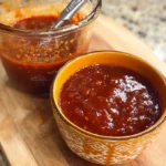 Spicy Peach BBQ Sauce in a jar with fresh peaches and spices