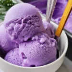 A bowl of vibrant purple ube ice cream topped with coconut flakes.