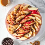 Delicious apple nachos topped with caramel sauce, nuts, and chocolate drizzle