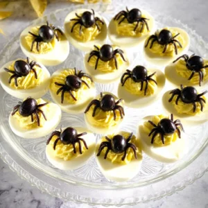 Spider deviled eggs decorated with olives and paprika for a spooky Halloween treat.