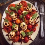 Spooky Halloween Caprese Salad with mozzarella, tomatoes, and basil leaves