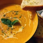 Bowl of creamy roasted vegetable soup garnished with fresh herbs