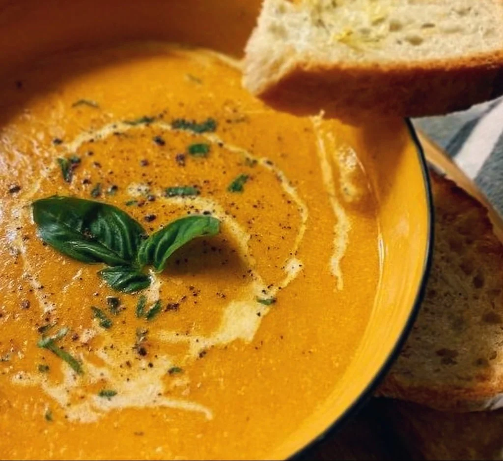Bowl of creamy roasted vegetable soup garnished with fresh herbs