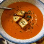 Bowl of homemade tomato soup garnished with fresh basil and croutons