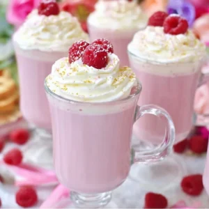 A cup of Raspberry White Hot Chocolate topped with whipped cream and fresh raspberries