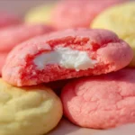 Freshly baked strawberry cheesecake cookies with a creamy topping and strawberry garnishes