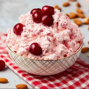 Bowl of Cherry Cheesecake Fluff dessert topped with fresh cherries and whipped cream.