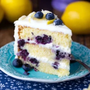 Slice of the best lemon blueberry cake topped with fresh blueberries