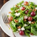 Grape salad with candied walnuts in a bowl, topped with fresh mint leaves.