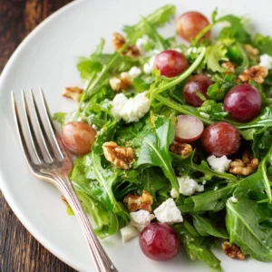 Grape salad with candied walnuts in a bowl, topped with fresh mint leaves.